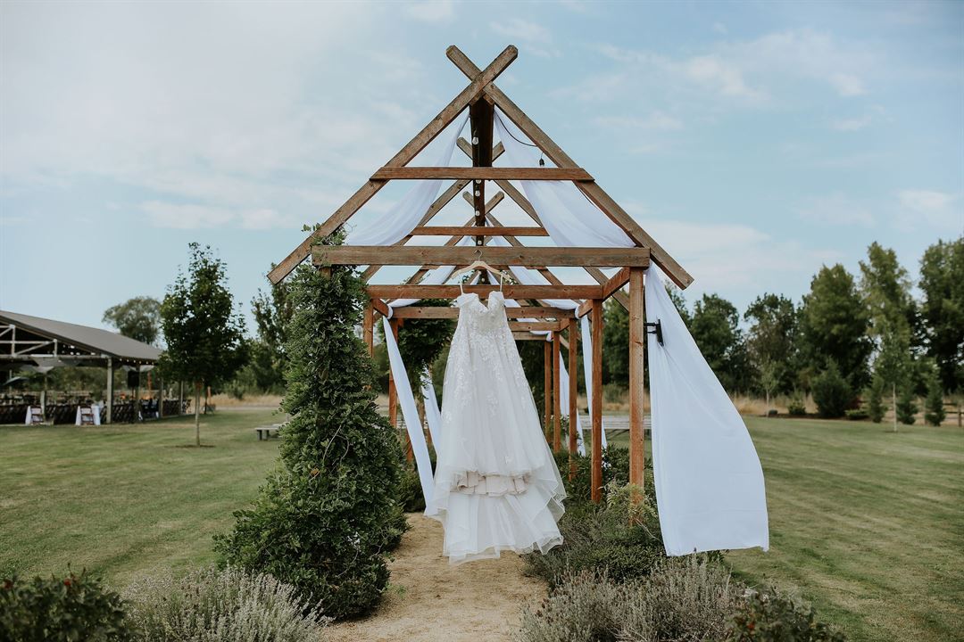 The garden arbor with white draping, the covered pavilion beyond — Creekside Farm